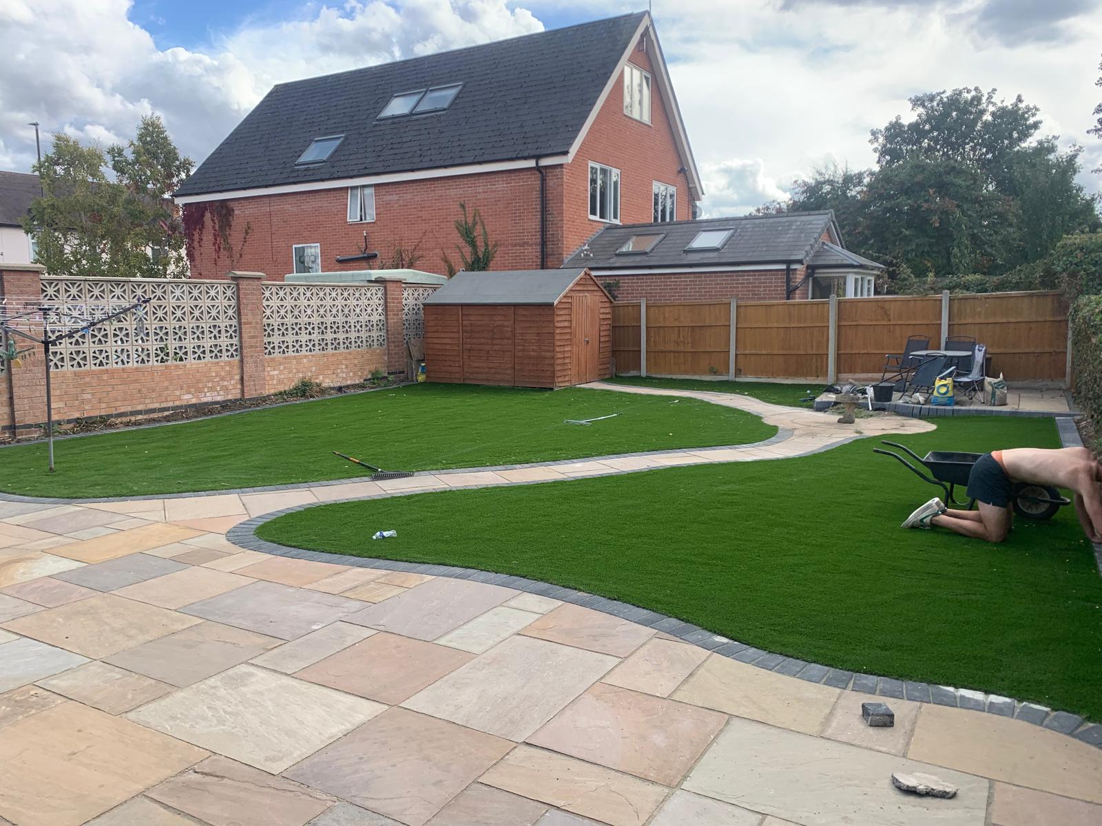 Rear garden with sandstone patio slabs, a curved path and a new grass lawn