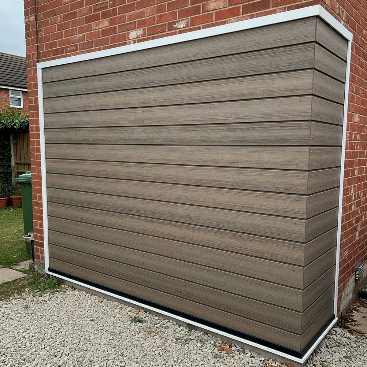 Horizontal composite cladding fitted to a garage wall with gravel at the base