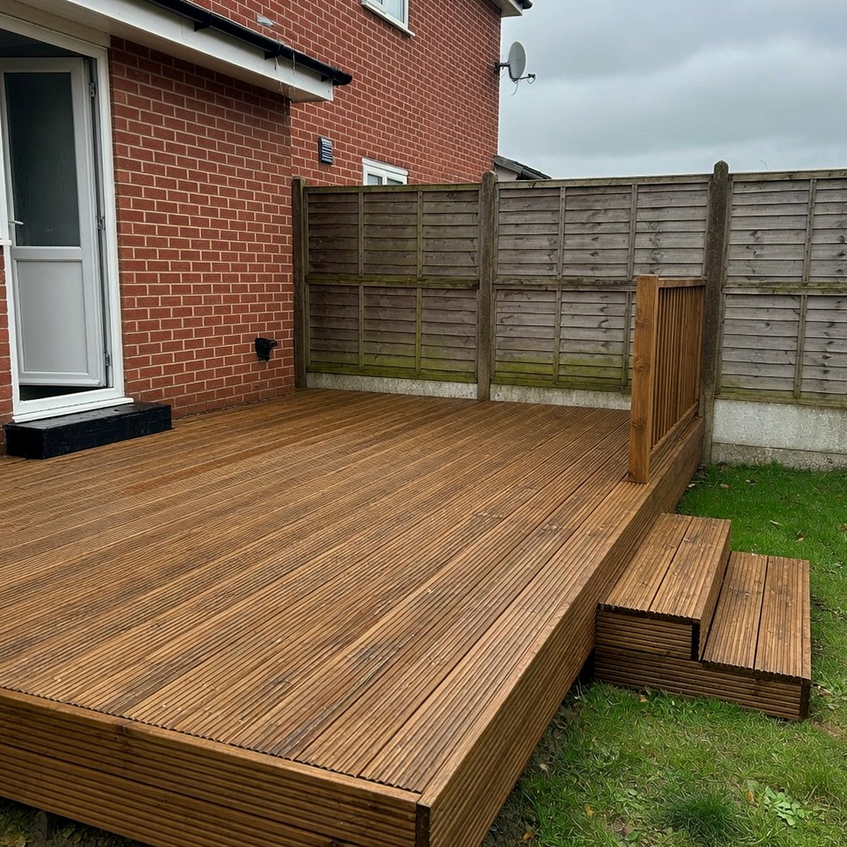 New timber decking with steps against a British brick house