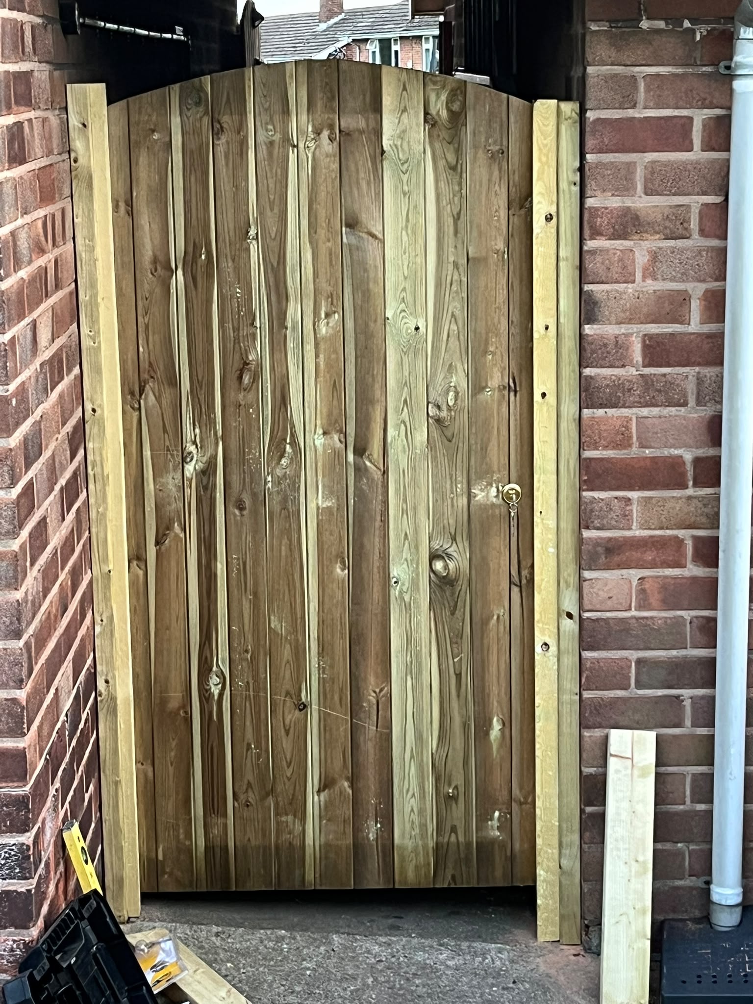 New timber side gate hung between red brick walls